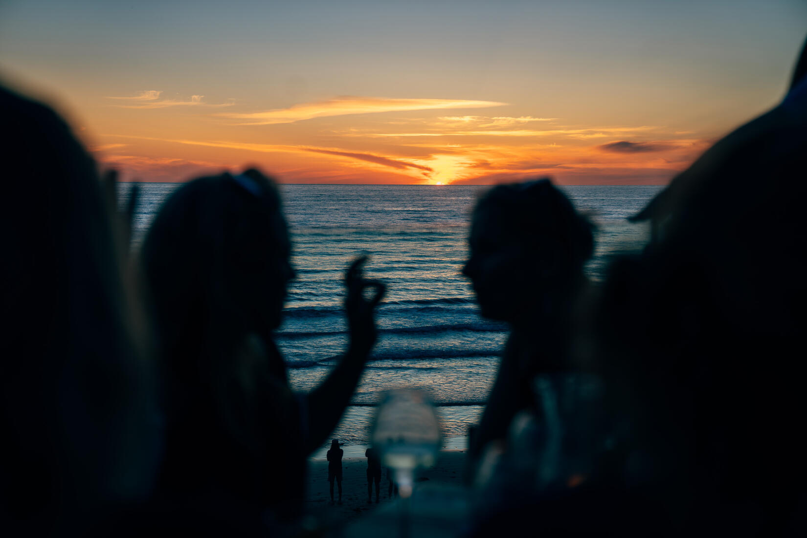 Couple enjoying a drink as the sun sets over the sea