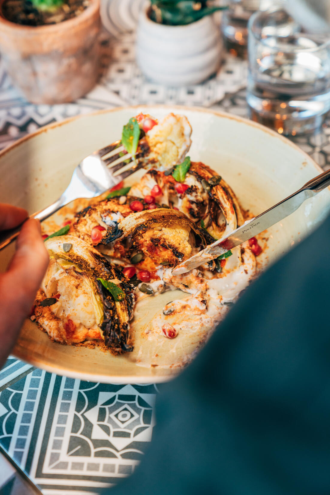 Plate of roasted cauliflower and pomegranate, with knife and fork