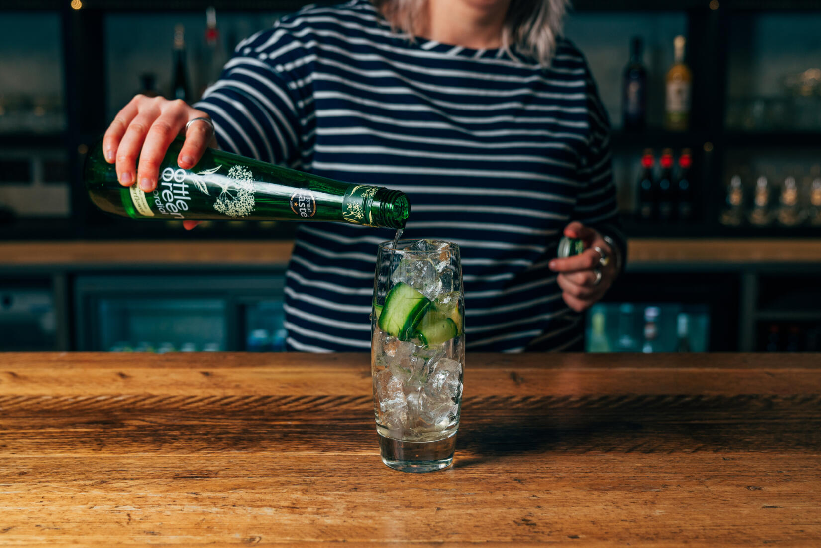 Glass of elderflower and mint cooler cocktail being poured