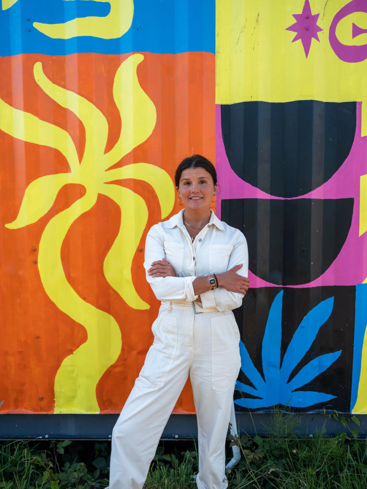 Clara Jonas stands in front of her colourful mural on the side of the beach food building at Watergate Bay