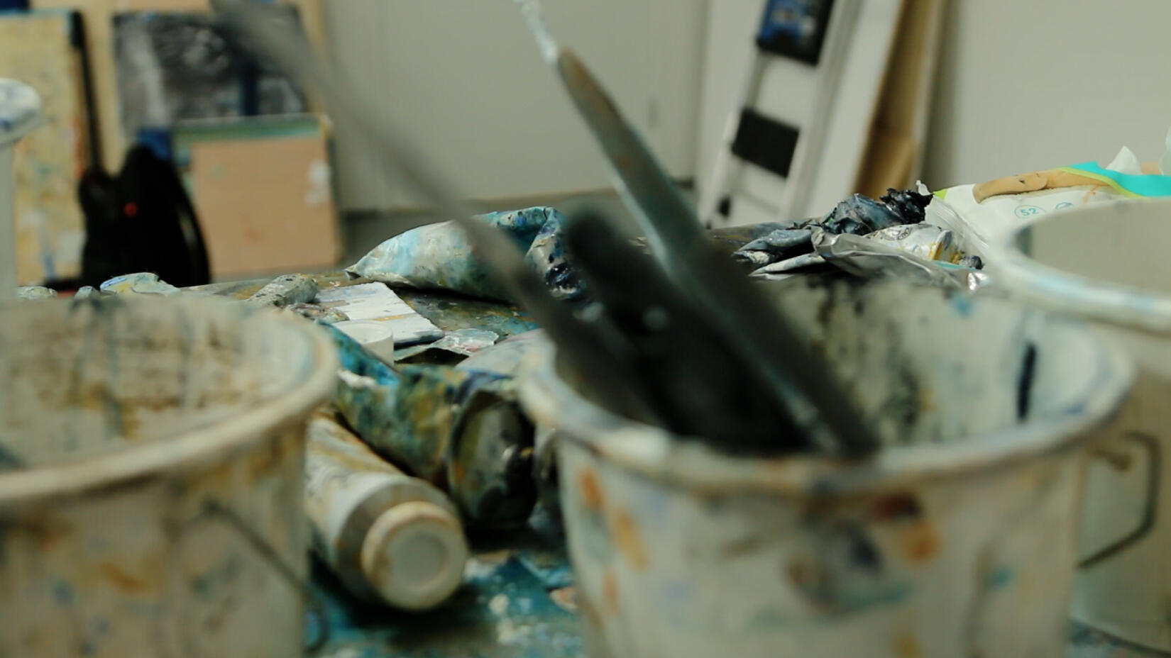 An artists studio with brushes and paint on the table