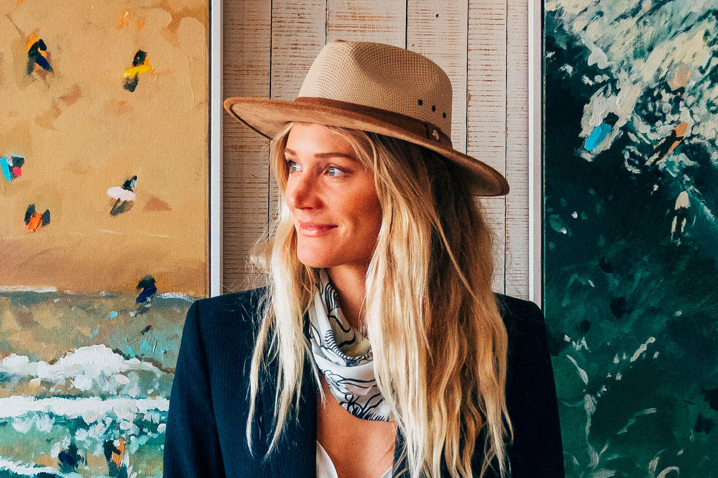 Image of artist Nina Brooke with her artwork displayed behind her