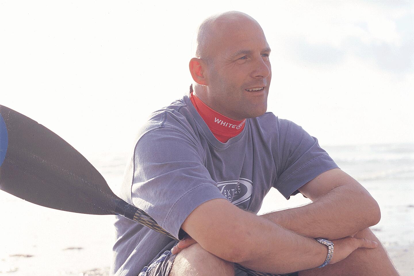 Carl sat on the beach with a sup paddle in his hand