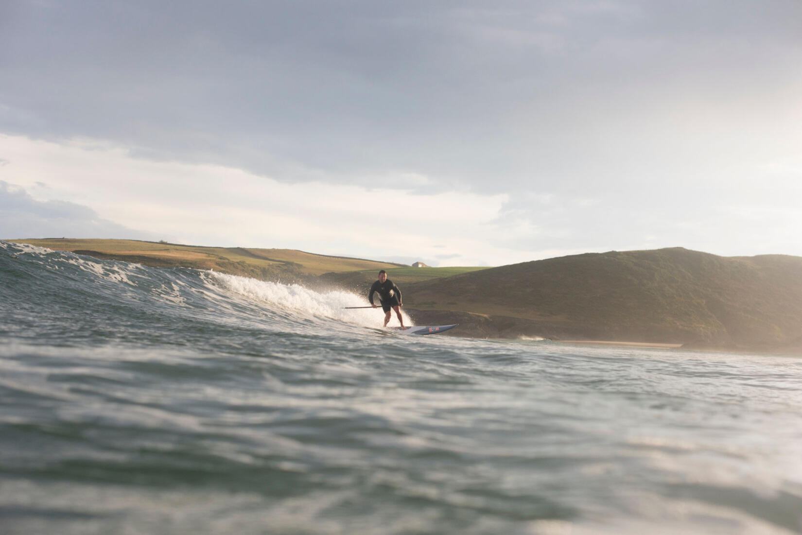 Andy Cameron rides a wave with a paddle and board