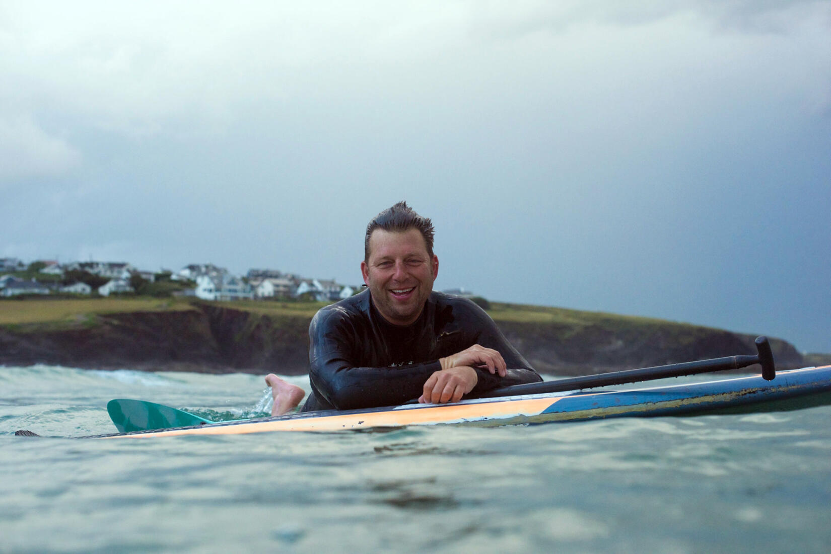 Andy Cameron leaning on his surfboard