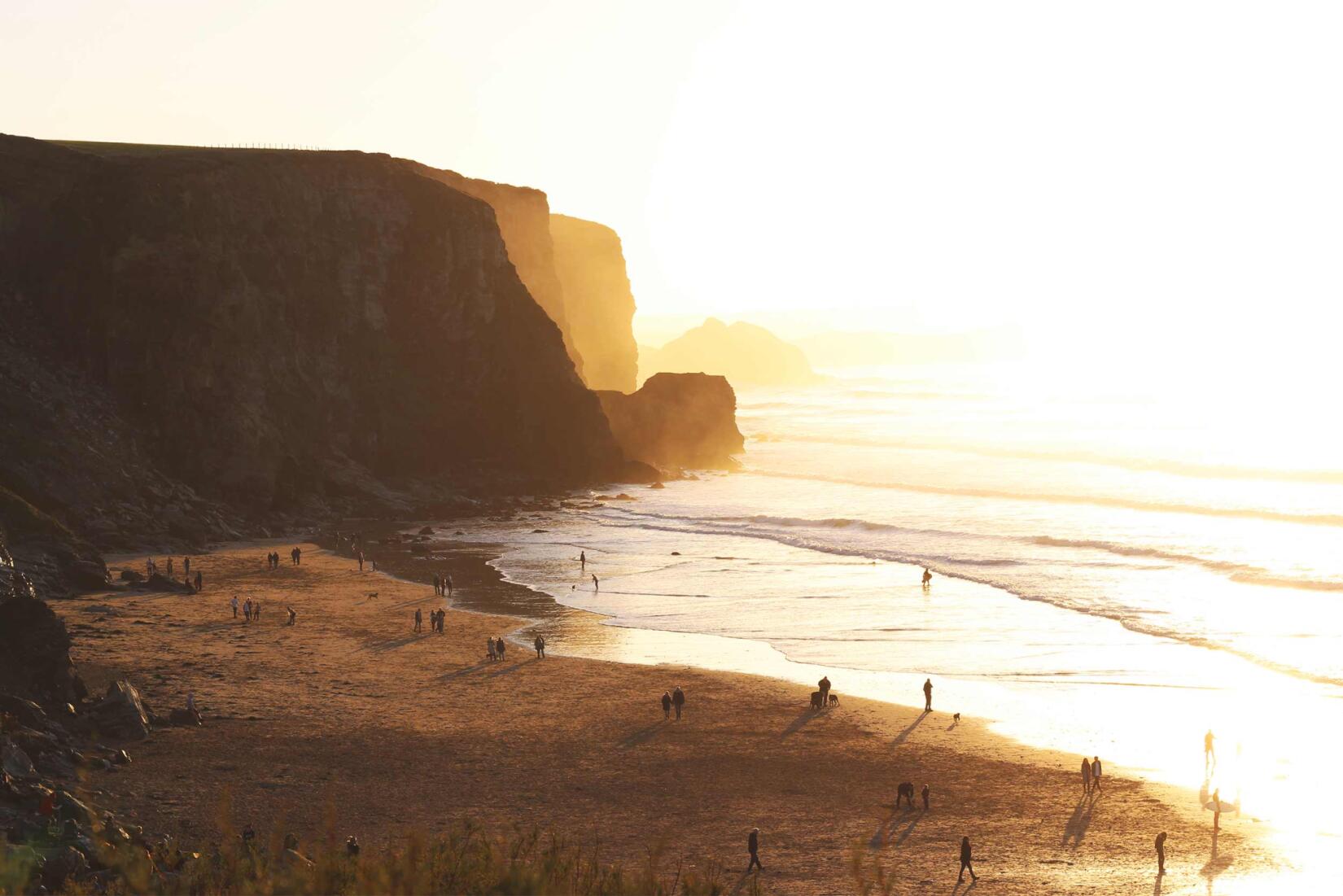 Dog Walkers On The Beach At Sunset