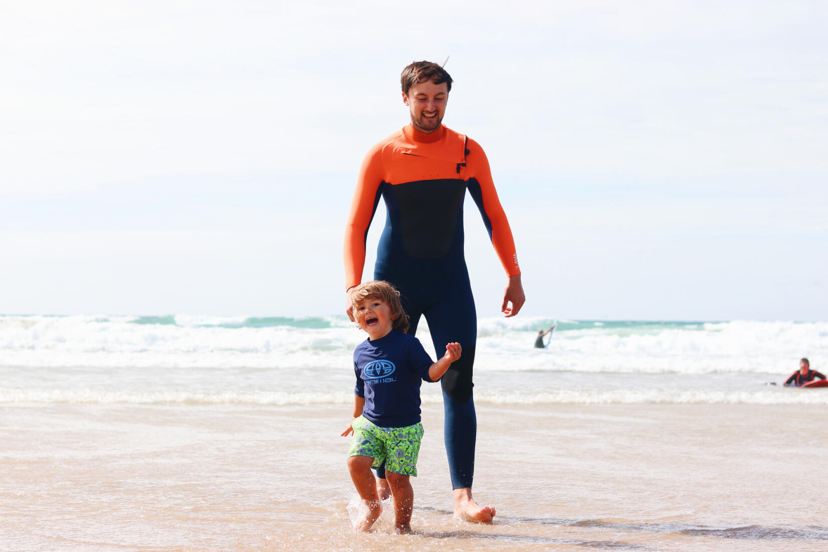 Father and son playing in the shallows on Watergate Bay beach