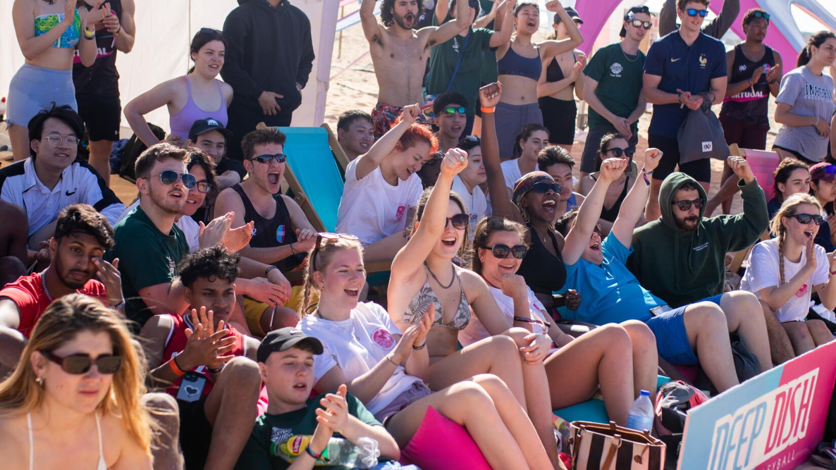 Crowds watch a volleyball match on the sand