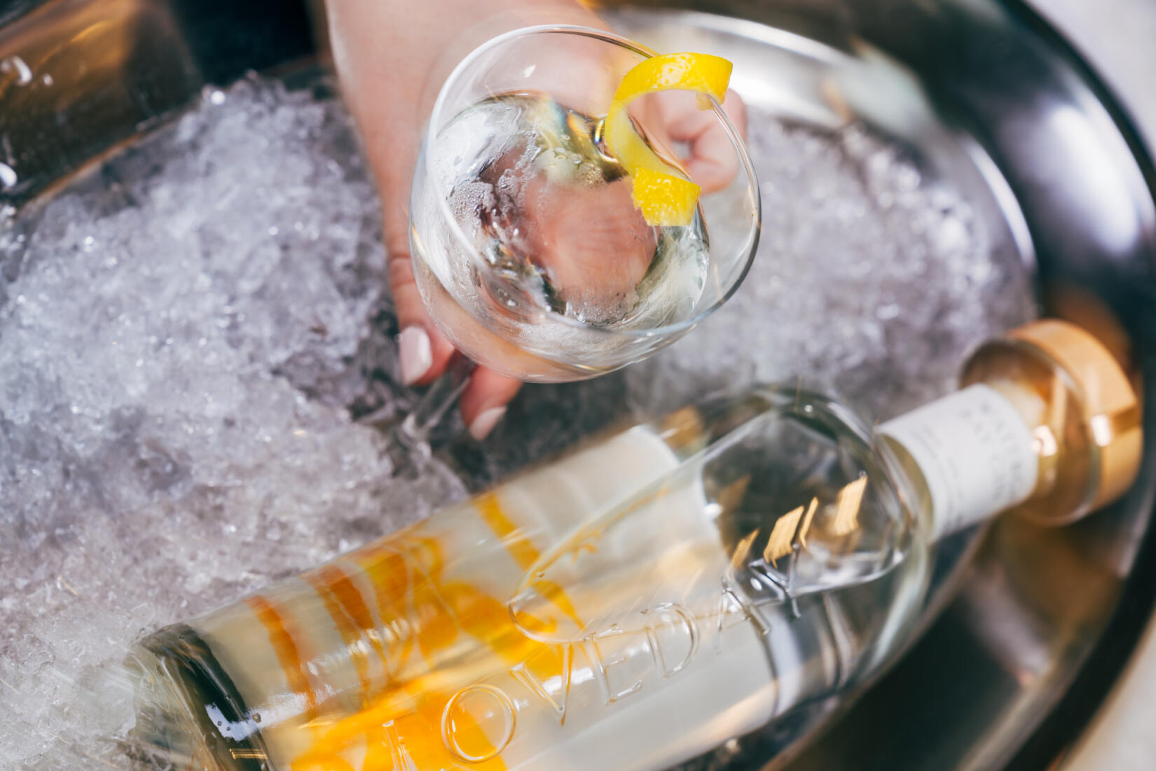 Glass of Après skate martini on a silver tray of ice next to a bottle of Loveday gin