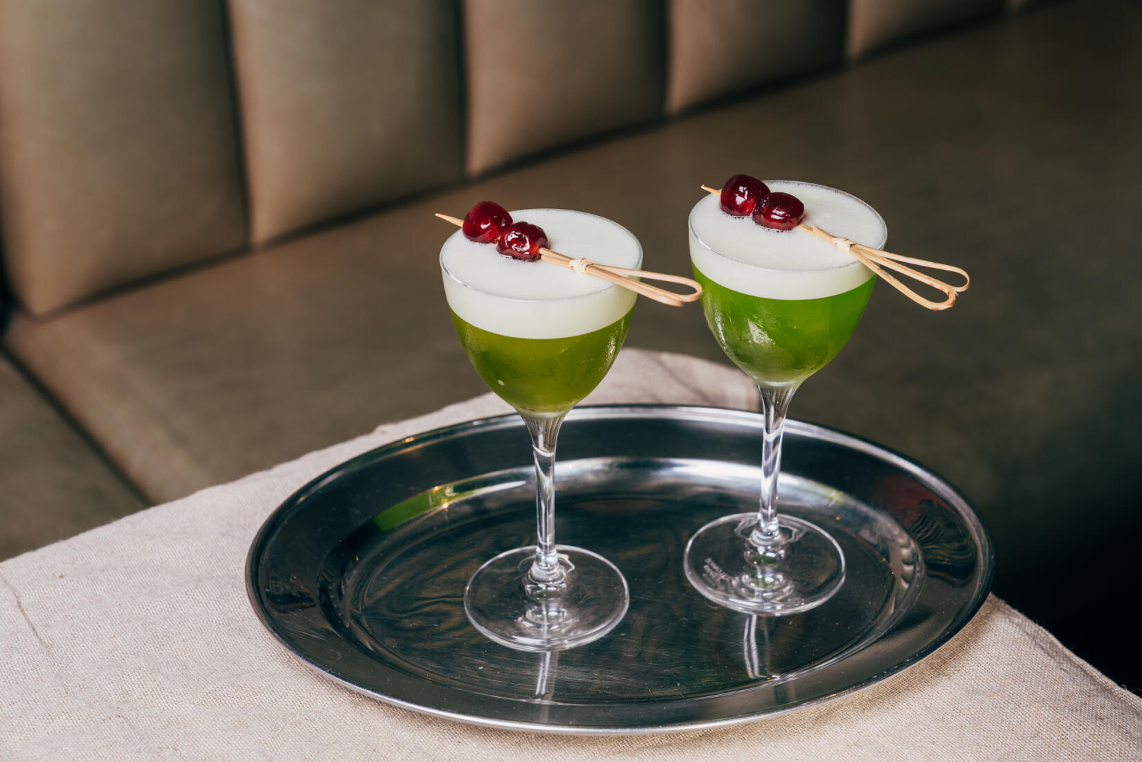 Two glasses of Mistletoe sour cocktail on a silver tray