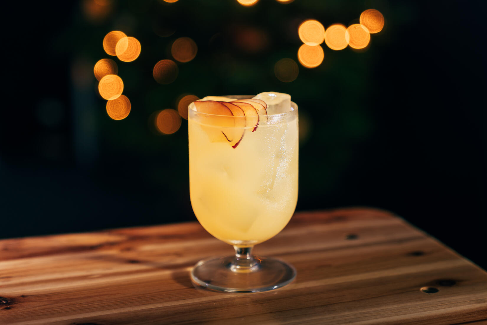 apple cocktail in a short bistro wine glass with plum garnish