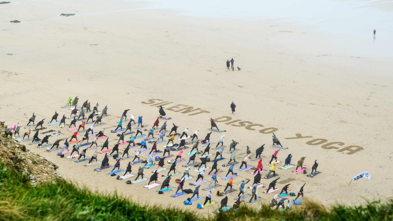 People doing yoga on the beach with silent disco headphones