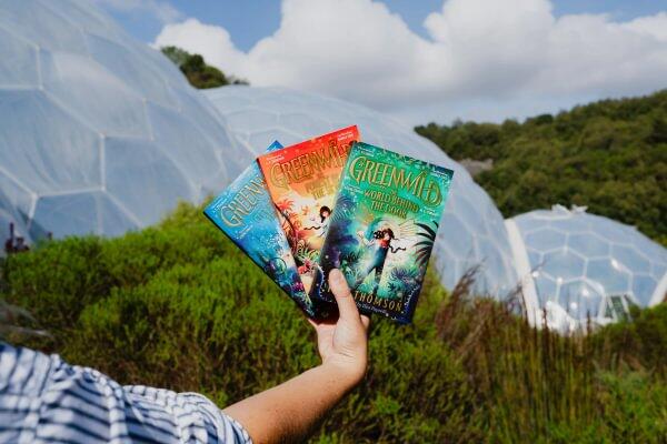 A selection of Greenwood by Pari Thomas books in front of the biomes at Eden Project