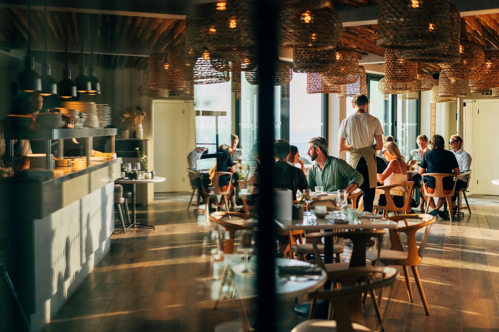 Interior of Zacry's on the sea wall, people eating at the restaurant in golden evening light
