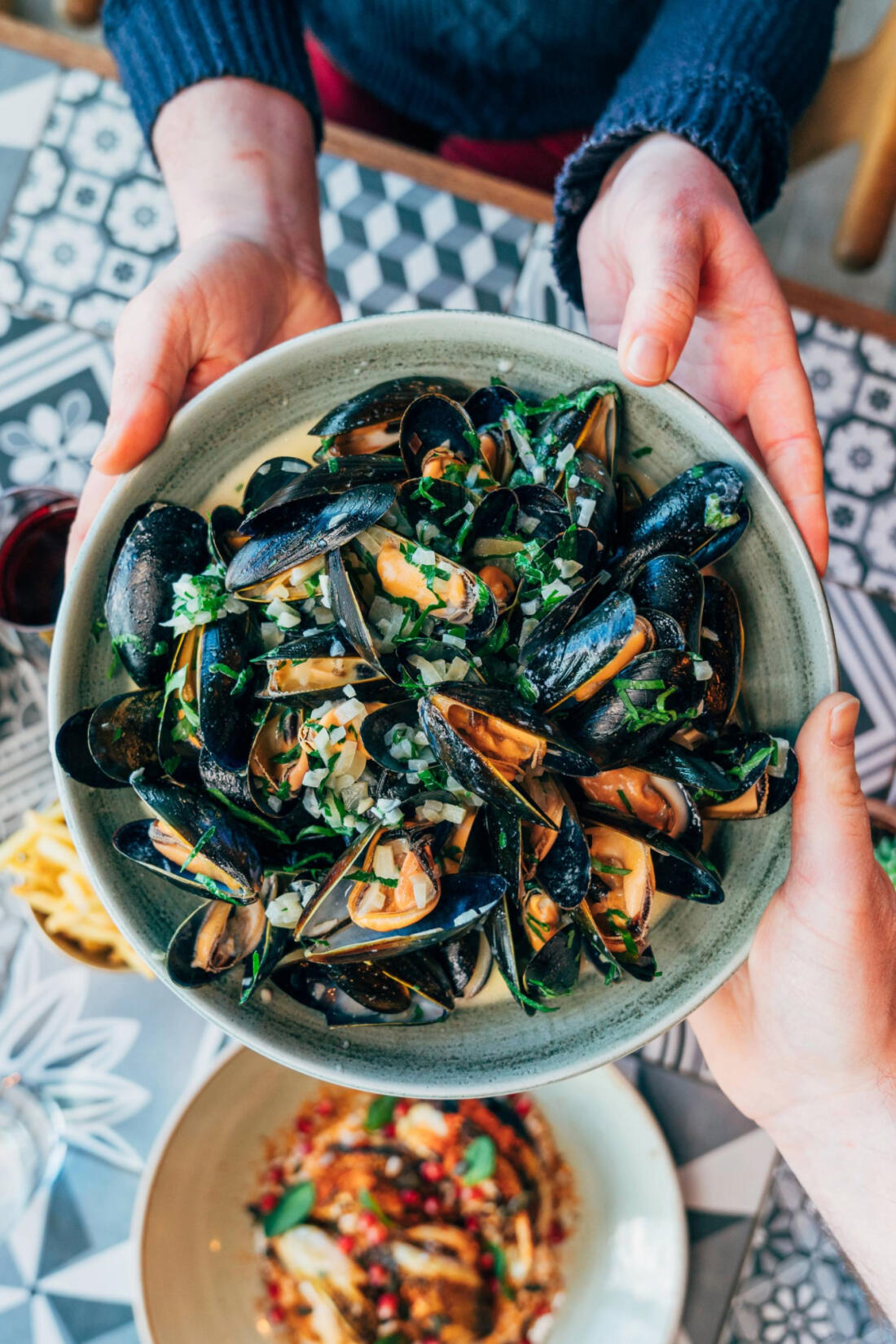 Bowl of mussels being passed across a table at The Beach Hut